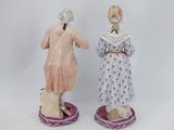 pair of porcelain figurines of women in dresses and hats