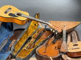a guitar, a violin case, and other musical instruments on a table