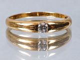 gros plan d'une bague en or surmontée d'un diamant