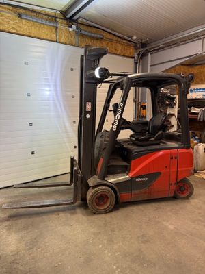 un chariot élévateur rouge garé dans un garage, à côté d'une porte de garage