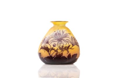 a yellow vase with flowers on it on a white surface