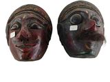une paire de masques en bois dont les visages sont peints sur fond blanc