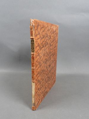an old book with a brown cover sitting on top of a table