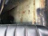 a dirty seat in the back of a car with rust on it