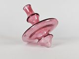 a pink glass object that is sitting on a white surface