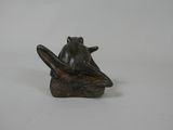 statue of a frog sitting on a branch with a book in its hand