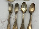 cinq cuillères en argent et cinq cuillères en argent posées sur une table