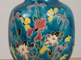 a blue vase with flowers on it sitting on a table