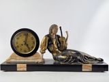 a statue of a woman sitting on a table next to a clock