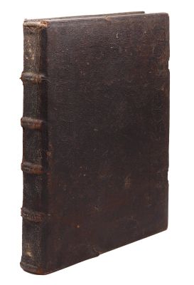 un vieux livre brun posé sur une surface blanche