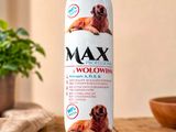 une photo d'un chien assis sur une table à côté d'une bouteille de Max