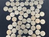 a close up of a pile of silver coins on a black surface
