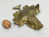 a nut and a brass leaf on a white surface