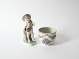 porcelain figurine of a boy and a cup on a white surface