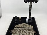 un vieux porte-monnaie en argent posé sur un plateau noir, à côté d'une croix