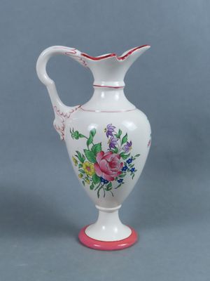 un vase blanc avec une anse rose et des fleurs peintes dessus