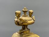 a gold vase with two birds on top of it
