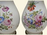 two vases with flowers painted on them sitting on a table