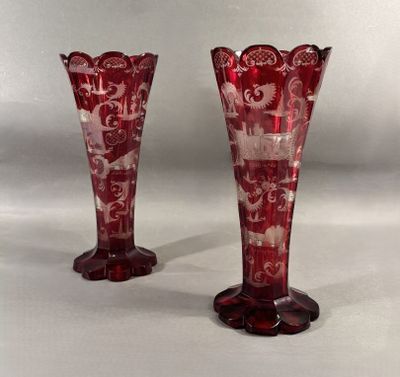 une paire de vases en verre rouge posés sur une table blanche
