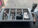 a tray with forks and spoons in it on a table
