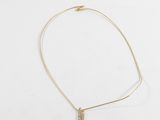 un collier en or avec un pendentif en forme de barre sur un fond blanc