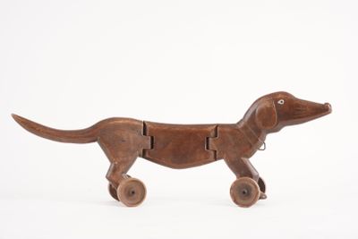 jouet en bois représentant un chien muni de roues, sur fond blanc