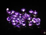 un gros plan sur un bouquet de pierres précieuses violettes posées sur une surface noire