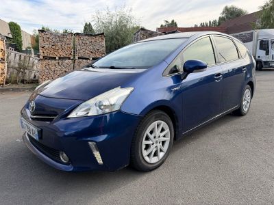 the blue toyota prius parked in a parking lot next to a pile of wood