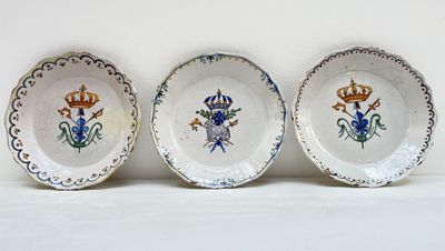 trois assiettes avec des motifs de fleurs et de couronnes sur une surface blanche