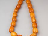 a close up of a necklace with orange beads on a gray surface