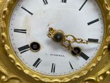 a gold clock with roman numerals on the face