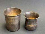 two silver cups sitting next to each other on a table
