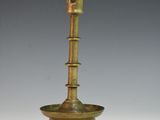 an antique brass candle holder on a white surface