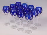 six blue wine glasses with white designs are lined up on a white surface