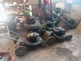 many lawn mowers that are sitting in the garage