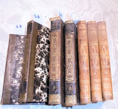 Plusieurs vieux livres sont alignés sur une nappe en dentelle