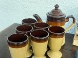 several cups and a teapot sit on a table next to a stack of books