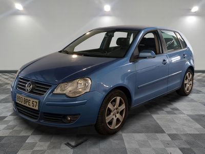 une voiture bleue garée dans une pièce au sol à damier et aux murs blancs
