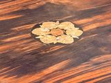 a small wooden table with a gold flower on it