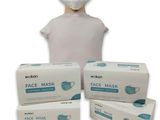 une personne portant un masque à côté de trois boîtes de masques