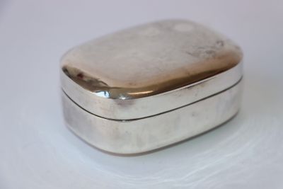 une boîte en argent posée sur une table blanche