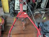 une tondeuse à gazon rouge dans un garage, à côté d'autres outils