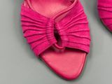 des chaussures roses ornées d'un nœud sur le côté, posées sur un fond gris