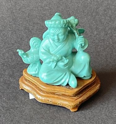 une figurine représentant un homme assis sur un socle en bois