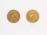 deux pièces d'or posées sur une surface blanche, dont l'une représente le visage d'un homme et l'autre la tête d'une femme