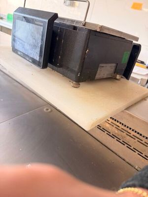 une personne debout devant un tapis roulant sur lequel se trouve une boîte