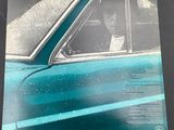 a blue car with a man sitting in the driver ' s seat