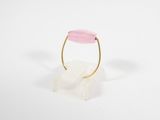 une bague en or sertie d'une pierre rose sur un support transparent