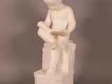 statue d'un garçon assis sur une caisse, en train de lire un livre