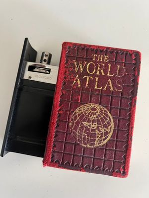 a small red book with a pen in it next to a cell phone